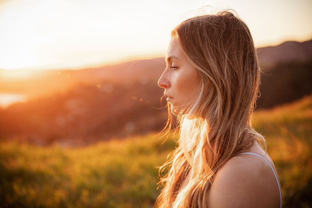 Woman meditating outdoors at sunset, symbolizing holistic anxiety treatment