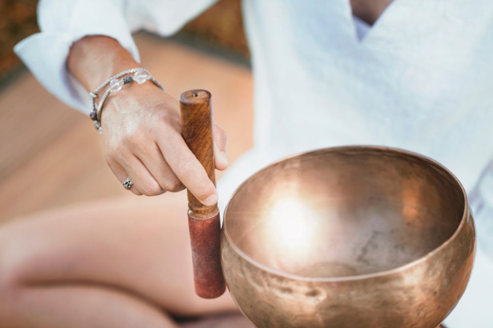 Close-up of a person using a Tibetan singing bowl during mental health therapy