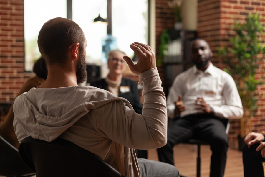 a man raising his right hand during group therapy